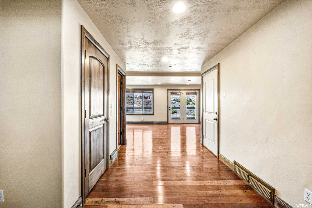 Hallway with light hardwood floors and a textured ceiling