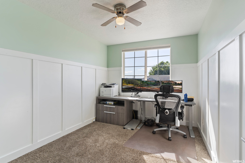 Carpeted home office featuring ceiling fan and a textured ceiling
