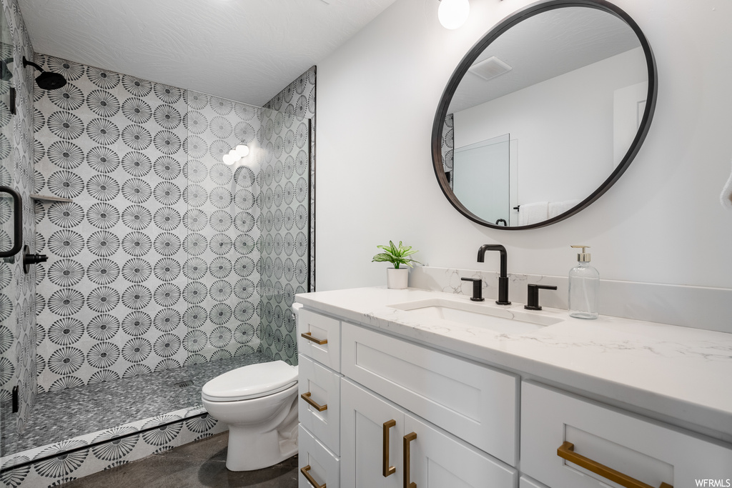 Bathroom featuring vanity, a tile shower, and mirror