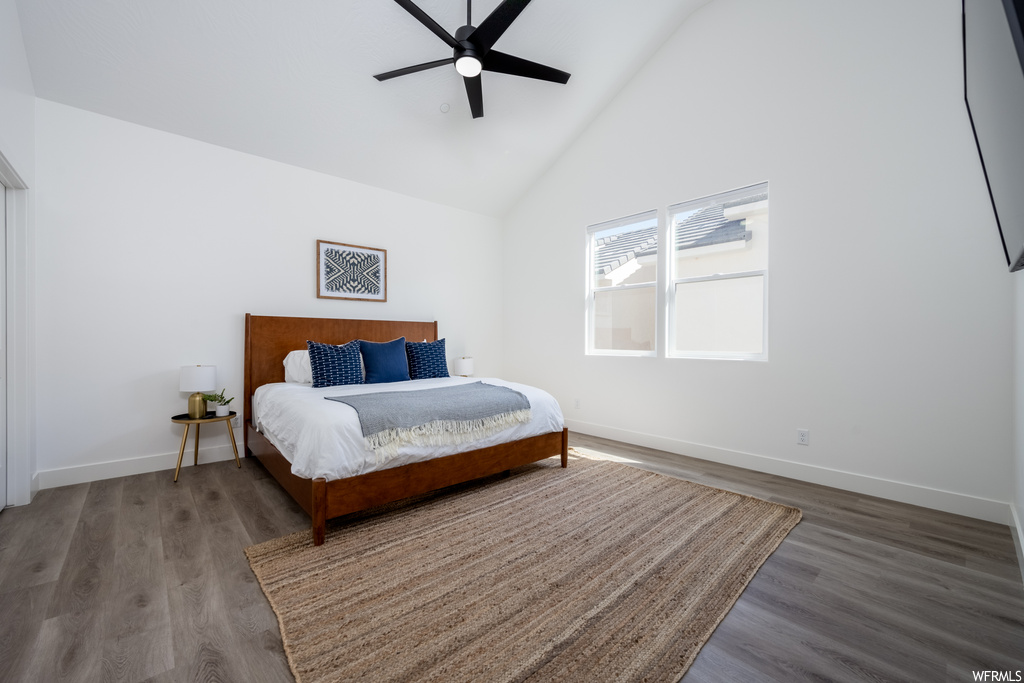 Bedroom featuring vaulted ceiling, a high ceiling, and light hardwood floors