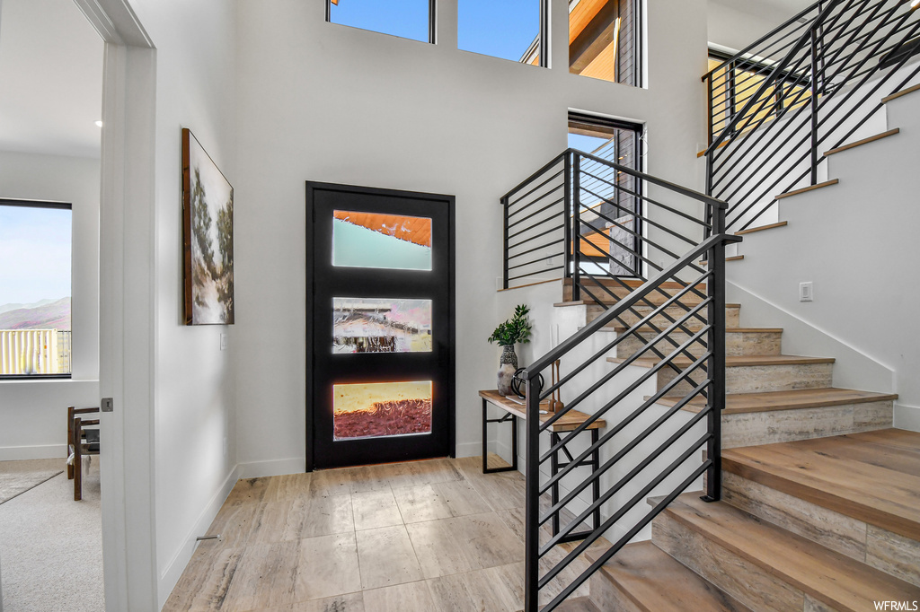 Foyer entrance with a towering ceiling, light hardwood flooring, and a wealth of natural light