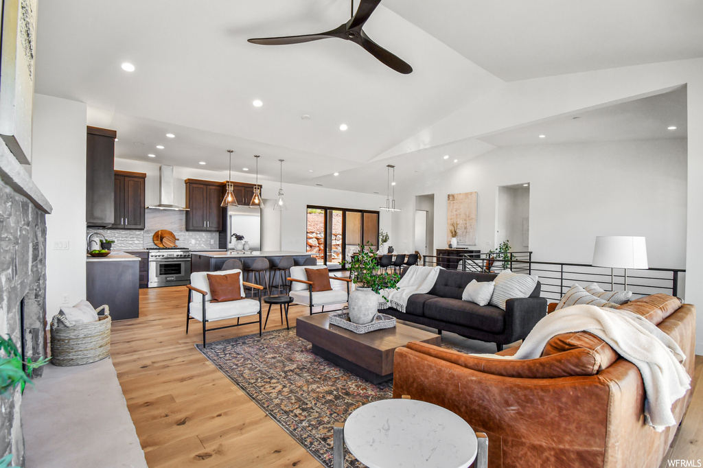 Living room featuring lofted ceiling, ceiling fan, light hardwood flooring, and a fireplace