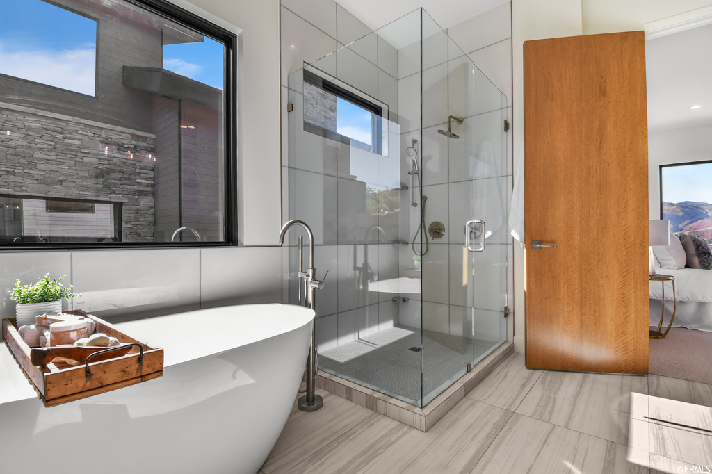 Bathroom with separate shower and tub, tile walls, and tile flooring