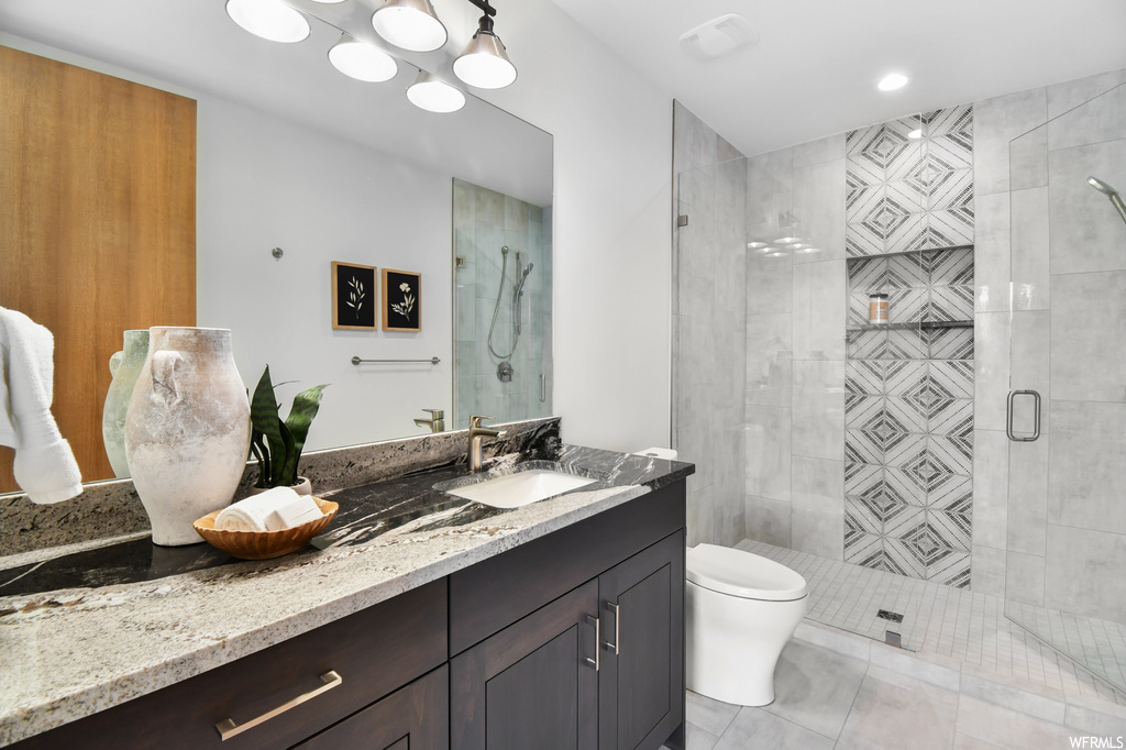 Bathroom featuring tile floors, toilet, walk in shower, and large vanity