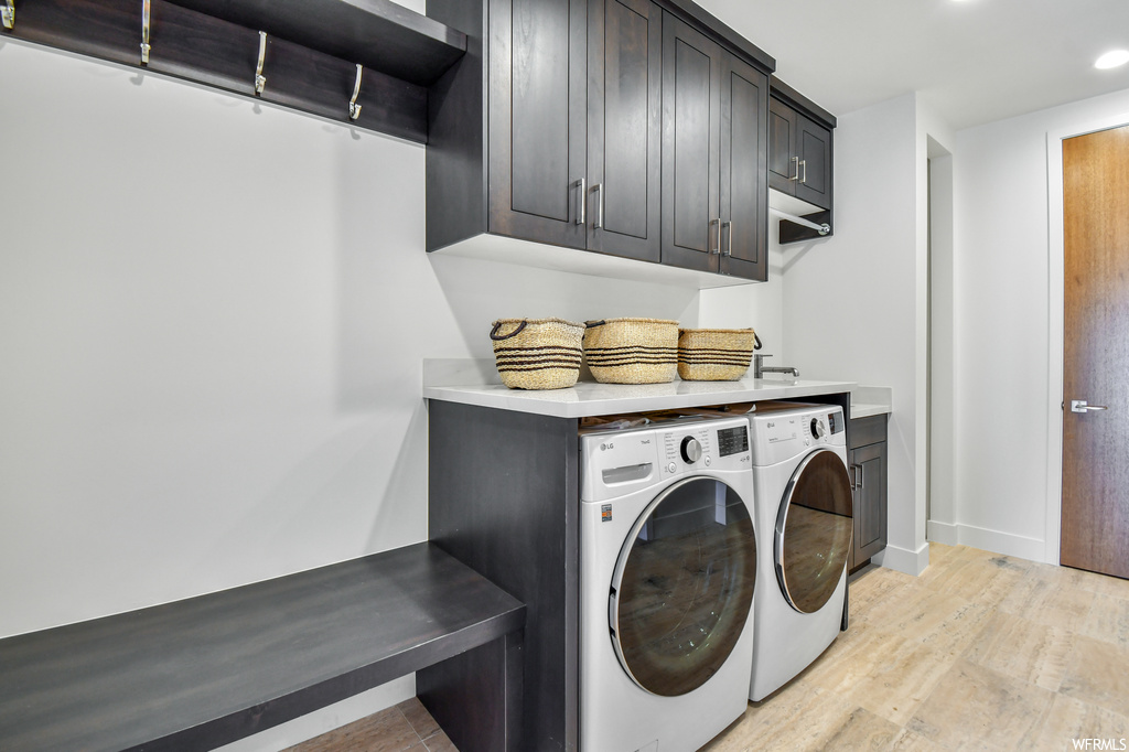 Laundry area with light hardwood floors, cabinets, and washer and clothes dryer