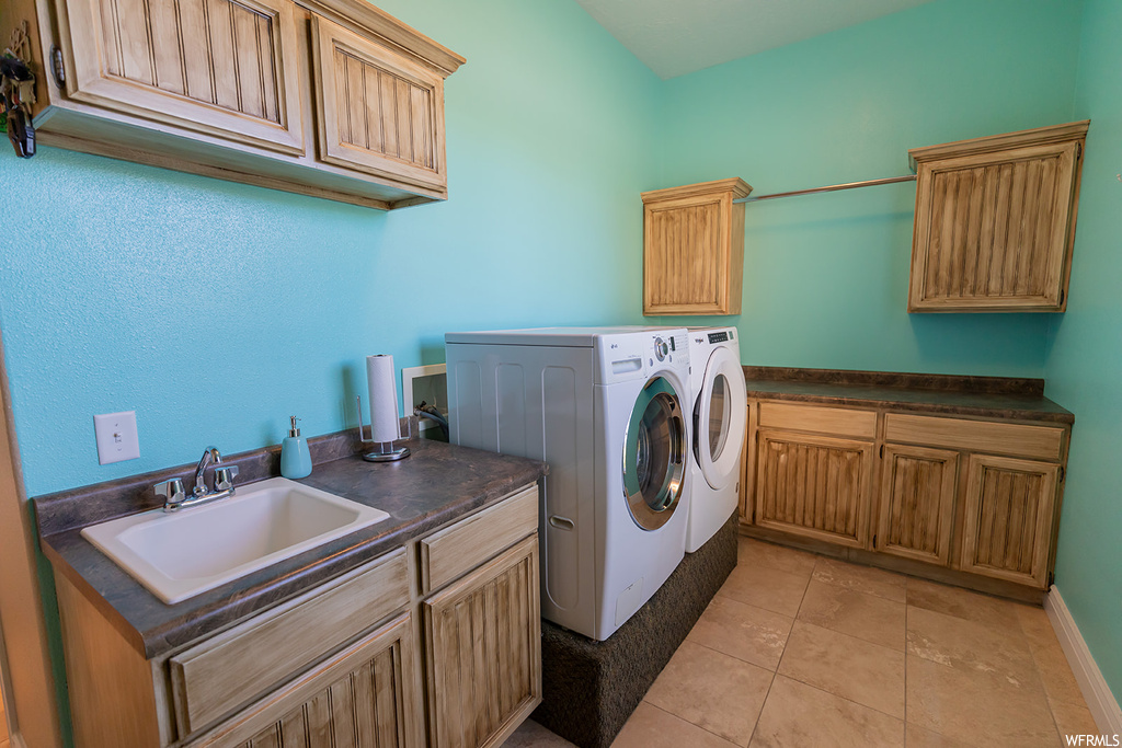 Clothes washing area featuring washer and dryer and light tile floors