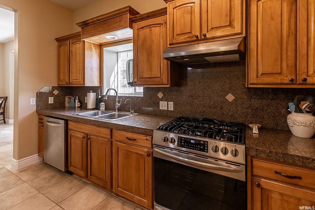 Kitchen with backsplash, brown cabinets, stainless steel appliances, and light tile floors