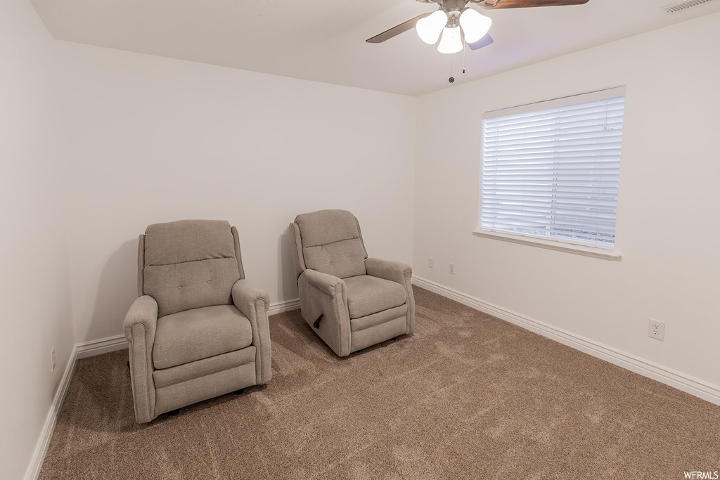 Living area with light carpet and ceiling fan