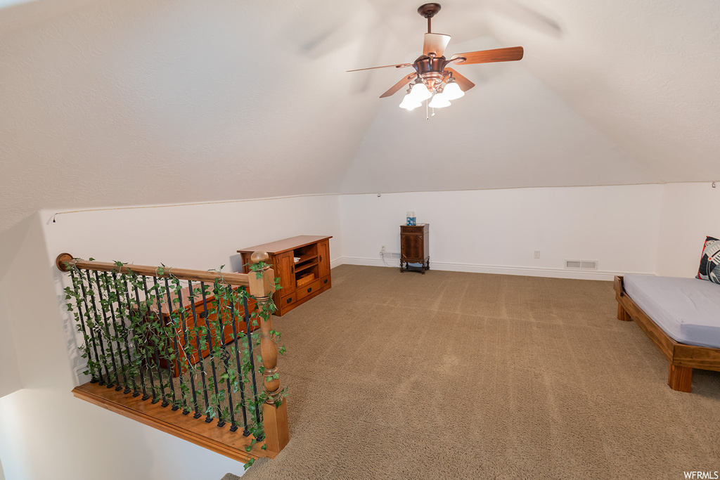 Additional living space featuring vaulted ceiling, light carpet, and ceiling fan