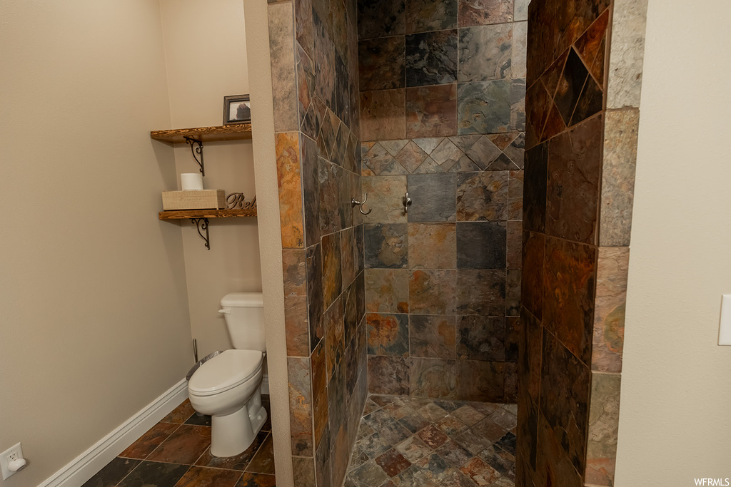 Bathroom featuring a tile shower and dark tile flooring