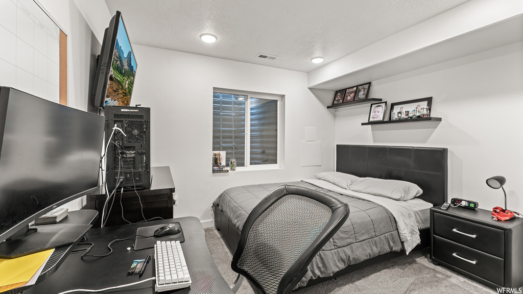 Bedroom with a textured ceiling and light carpet