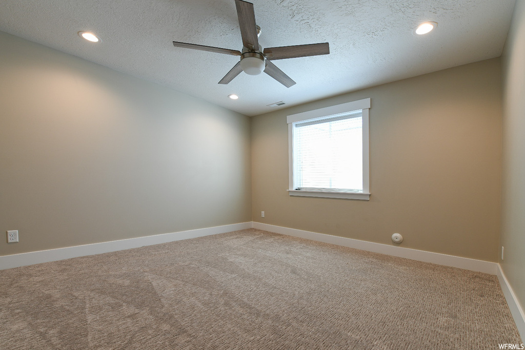 Unfurnished room with ceiling fan, light carpet, and a textured ceiling