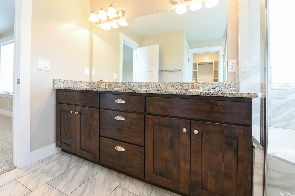 Bathroom featuring dual large bowl vanity, mirror, and light tile flooring