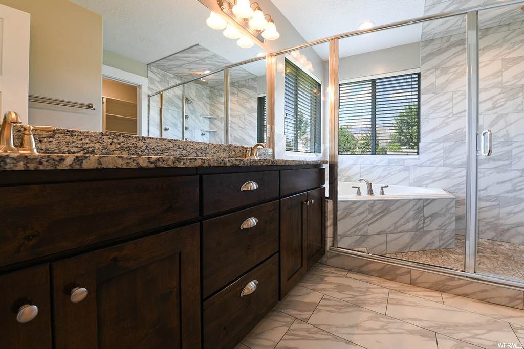 Bathroom featuring vanity, separate shower and tub enclosures, mirror, and light tile floors