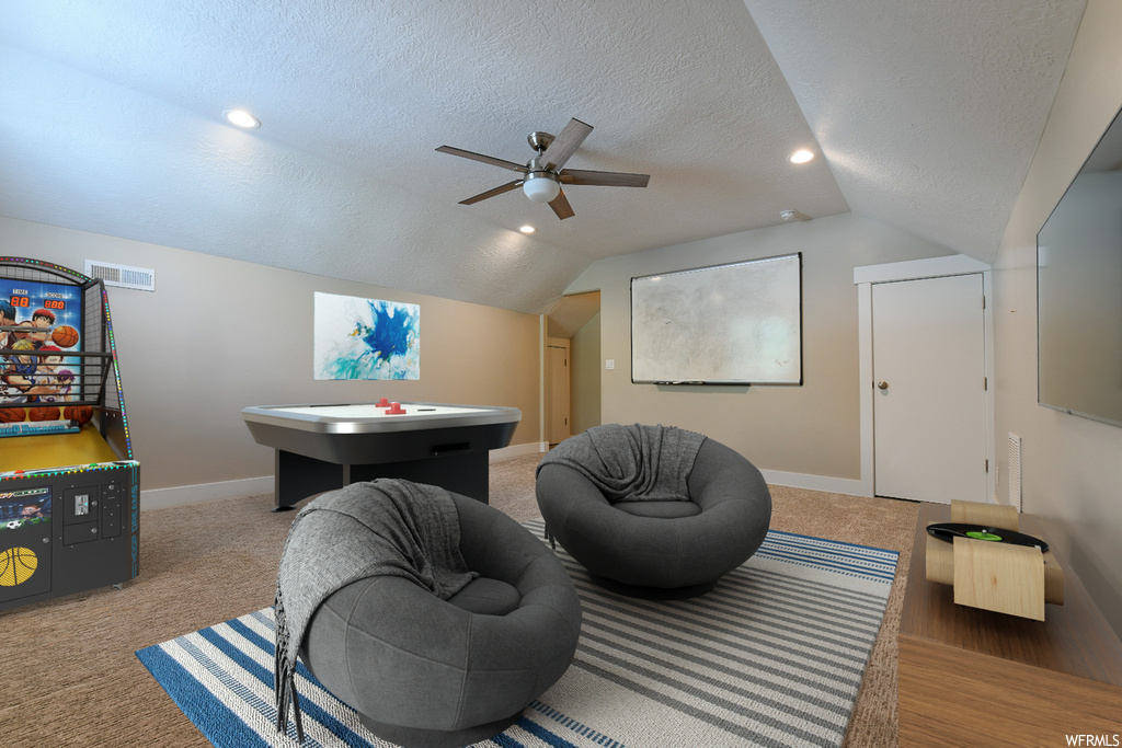 Rec room with light carpet, lofted ceiling, and a textured ceiling