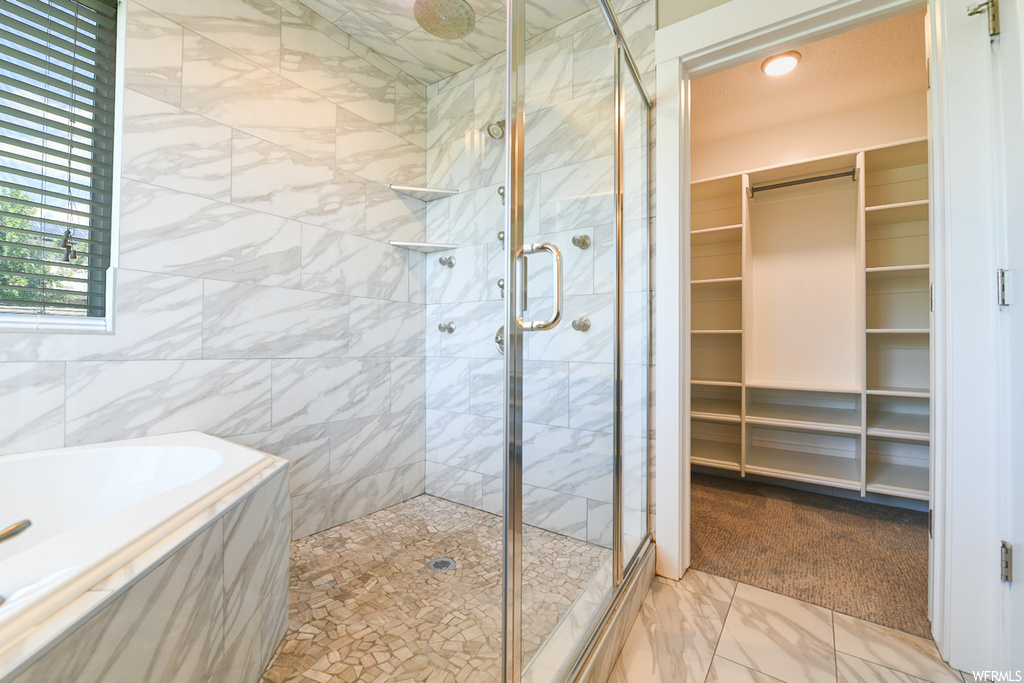 Bathroom with independent shower and bath, tile walls, and light tile floors