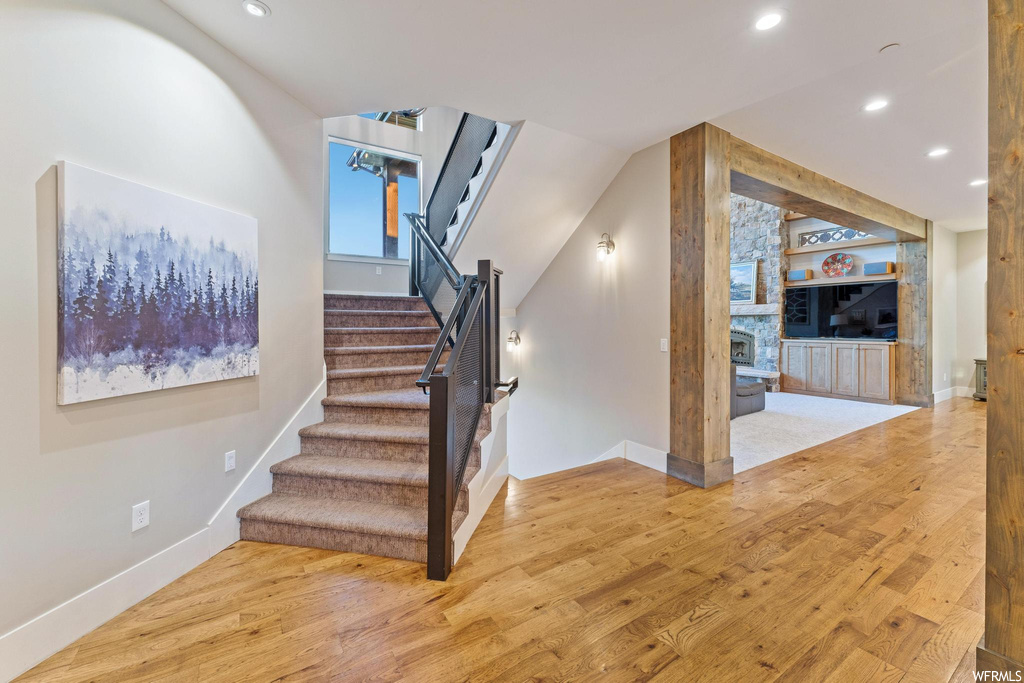 Stairs featuring light hardwood floors and a fireplace