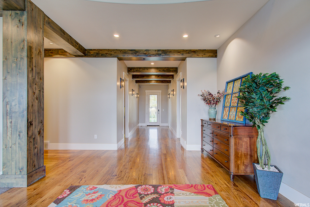Hall with beam ceiling and light hardwood flooring