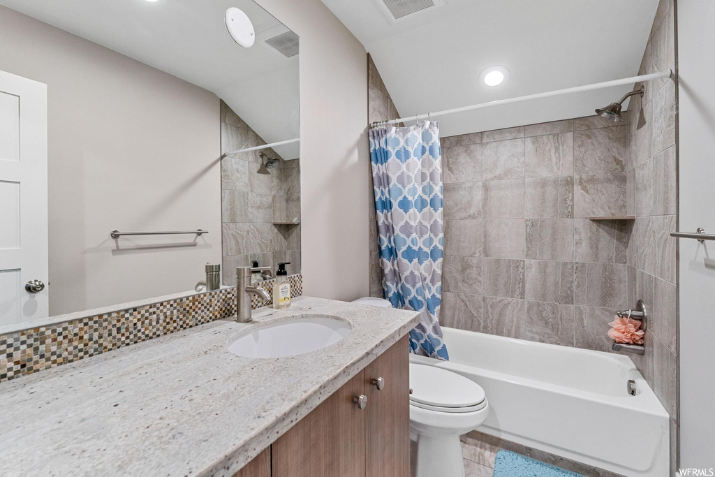 Full bathroom featuring vanity with extensive cabinet space, mirror, shower / tub combo, and light tile floors