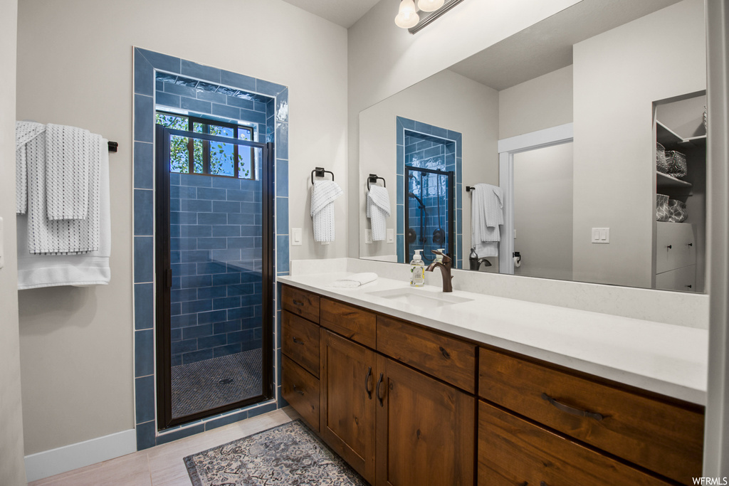 Bathroom with an enclosed shower, tile floors, mirror, and vanity