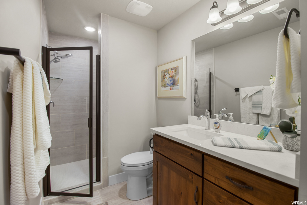 Bathroom featuring vanity, mirror, a shower with shower door, and light tile floors