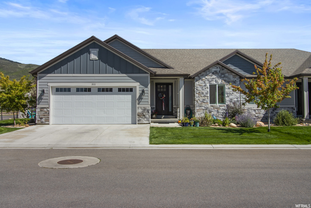 Craftsman-style home featuring garage and a front lawn