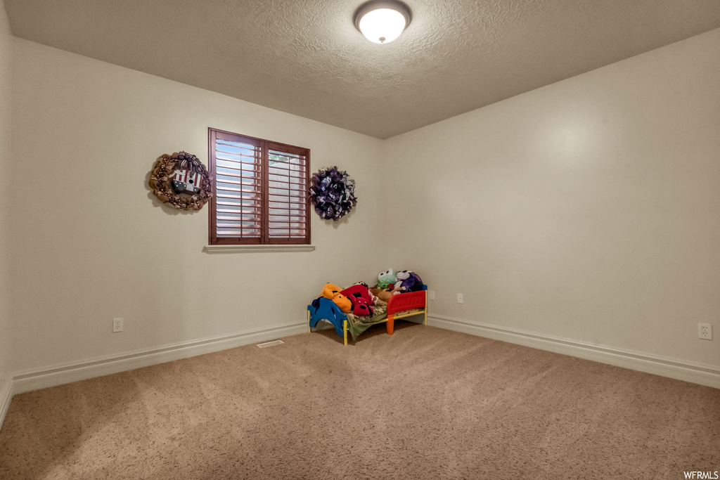 Playroom featuring light carpet and a textured ceiling