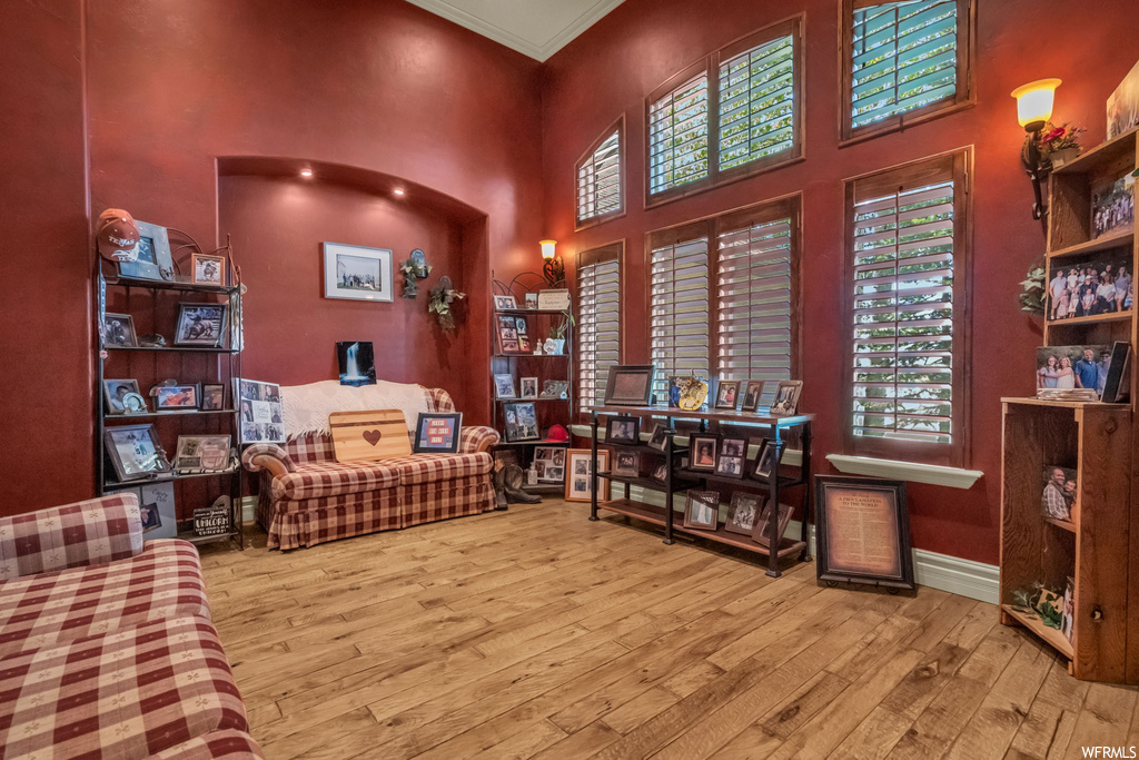 Sitting room with a high ceiling, light hardwood floors, and crown molding