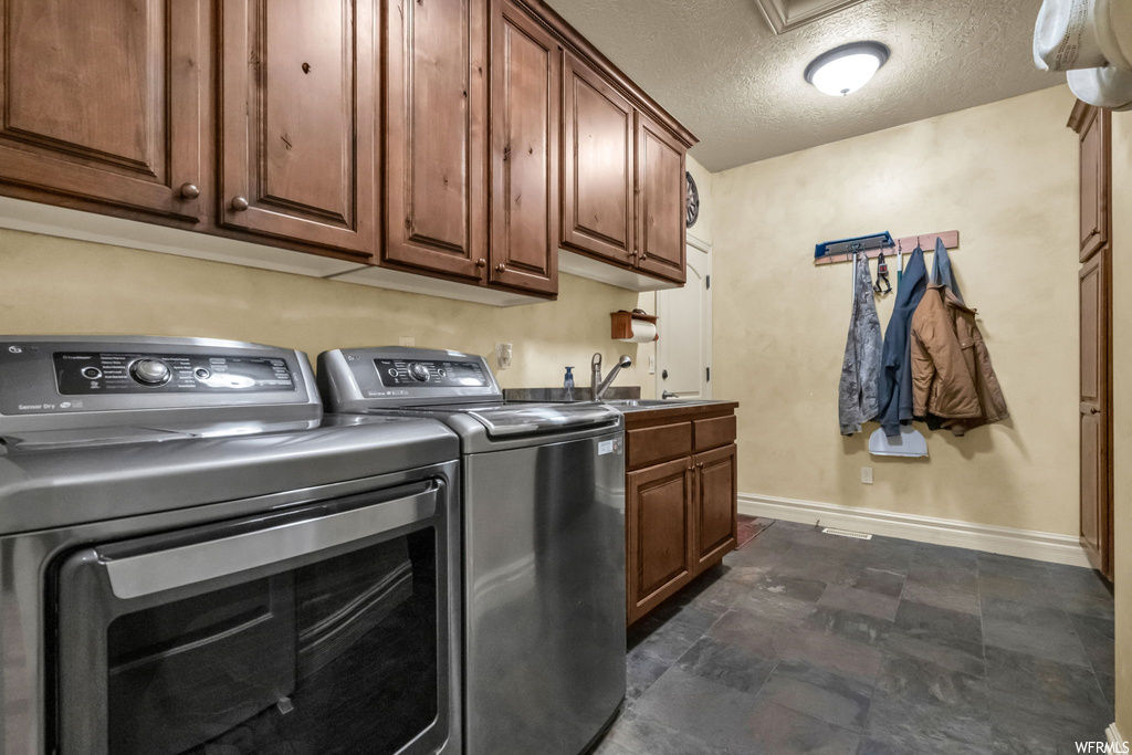 Laundry room featuring tile flooring, a textured ceiling, and washing machine and clothes dryer