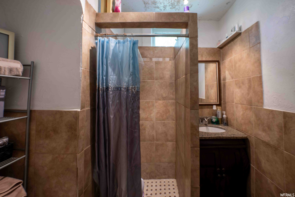 Bathroom with tile walls, curtained shower, mirror, and vanity