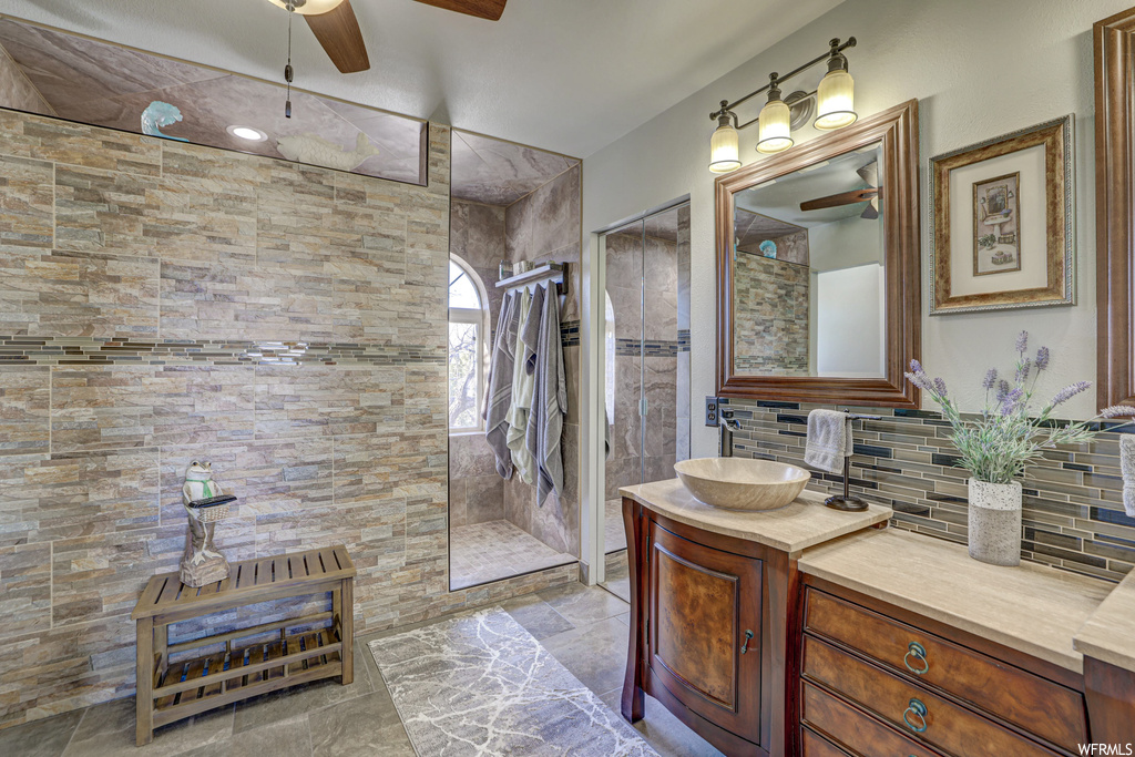 Bathroom featuring tile flooring, tasteful backsplash, ceiling fan, and vanity