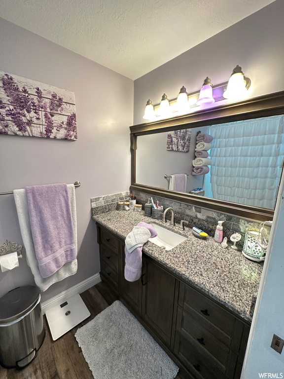 Bathroom featuring dark hardwood flooring, a textured ceiling, mirror, and vanity