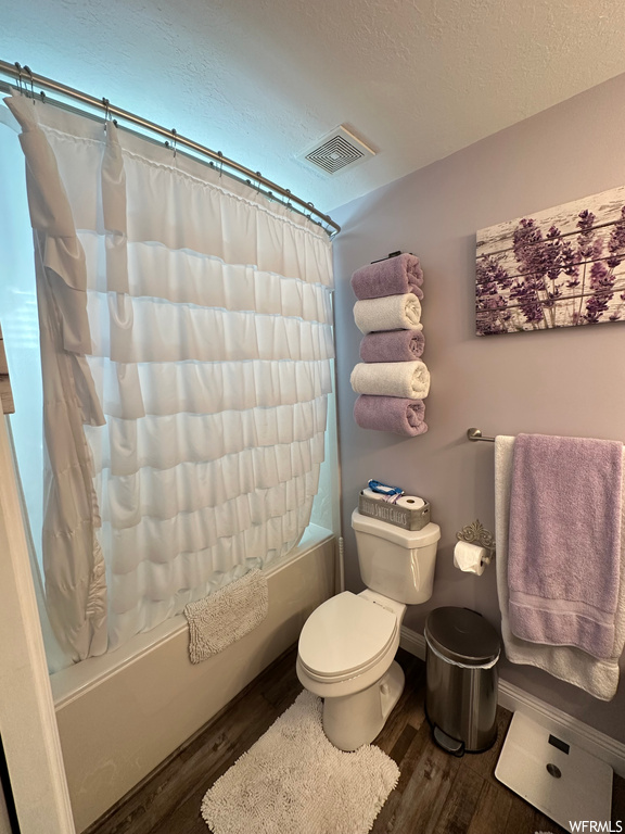 Bathroom featuring shower / tub combo, a textured ceiling, and hardwood floors