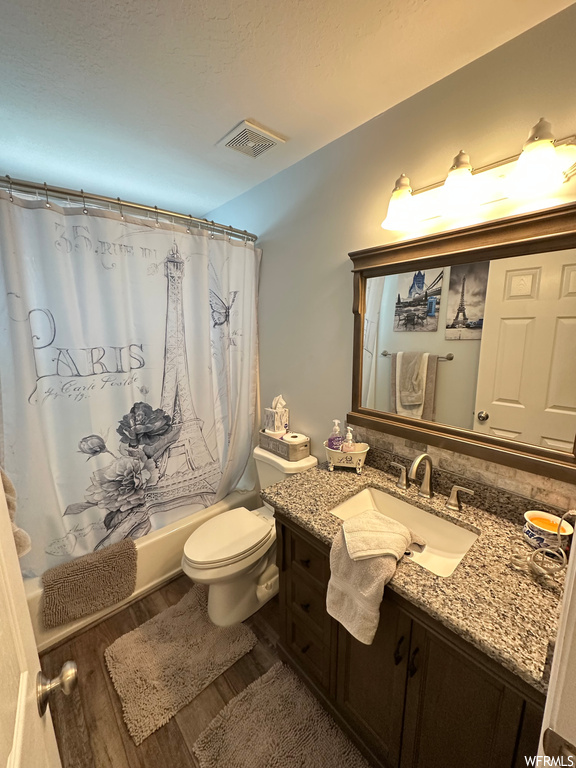 Full bathroom featuring hardwood floors, oversized vanity, mirror, and shower / bath combo