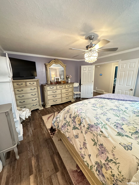 Hardwood floored bedroom with ceiling fan, a textured ceiling, and crown molding