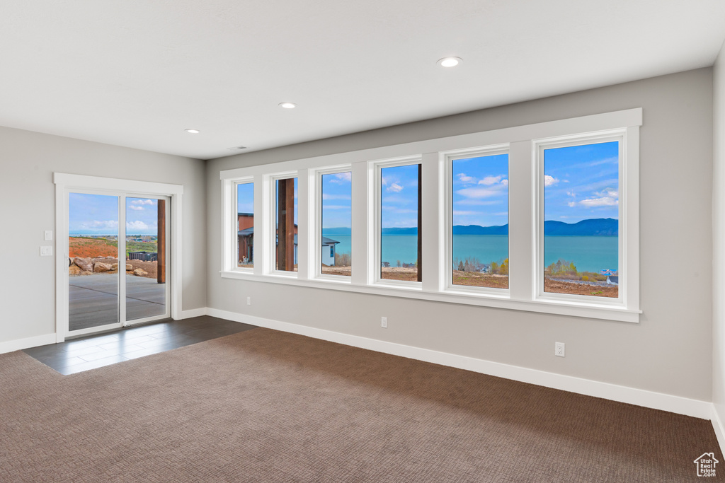 Carpeted spare room featuring a water view and plenty of natural light