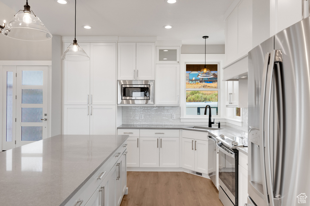 Kitchen featuring stainless steel appliances, white cabinets, sink, and light hardwood / wood-style flooring