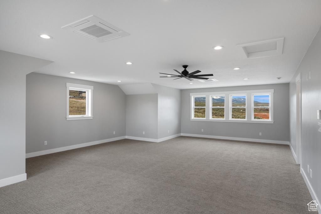 Spare room featuring vaulted ceiling, ceiling fan, and carpet floors