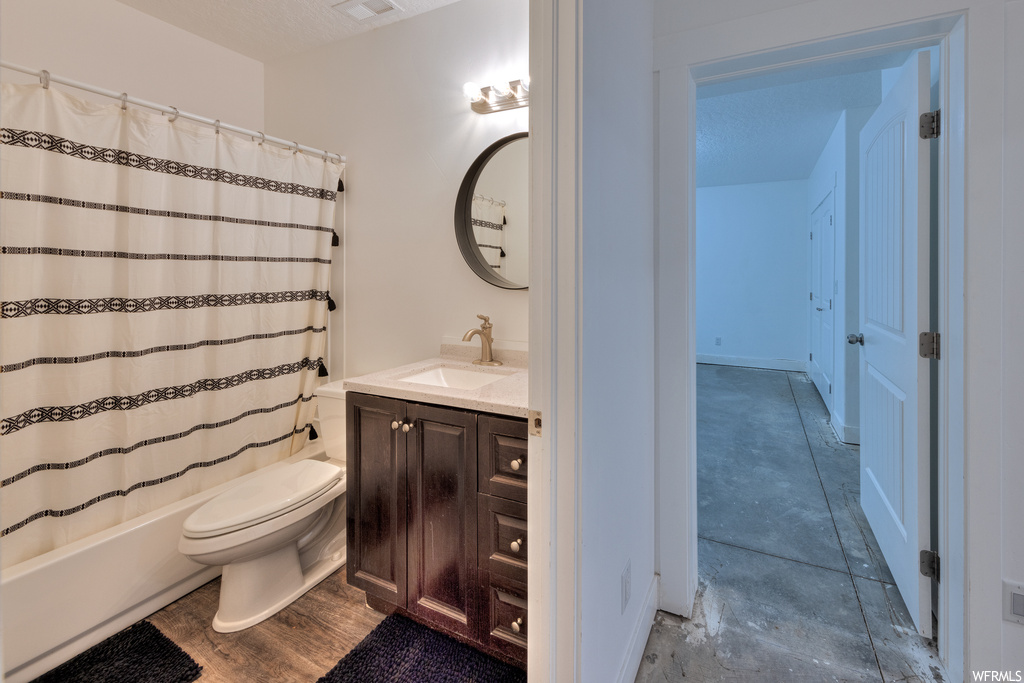 Full bathroom with vanity, a textured ceiling, mirror, hardwood flooring, and shower / bath combo