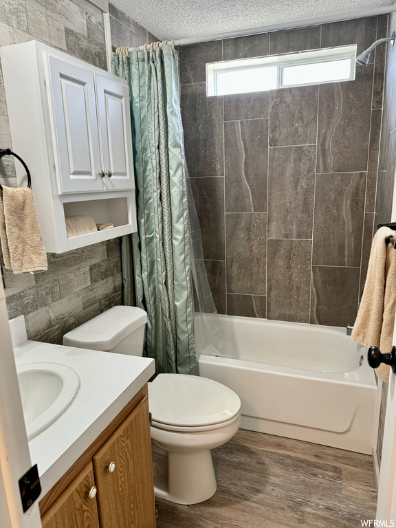 Full bathroom featuring shower / bathtub combination with curtain, toilet, a textured ceiling, hardwood / wood-style floors, and vanity