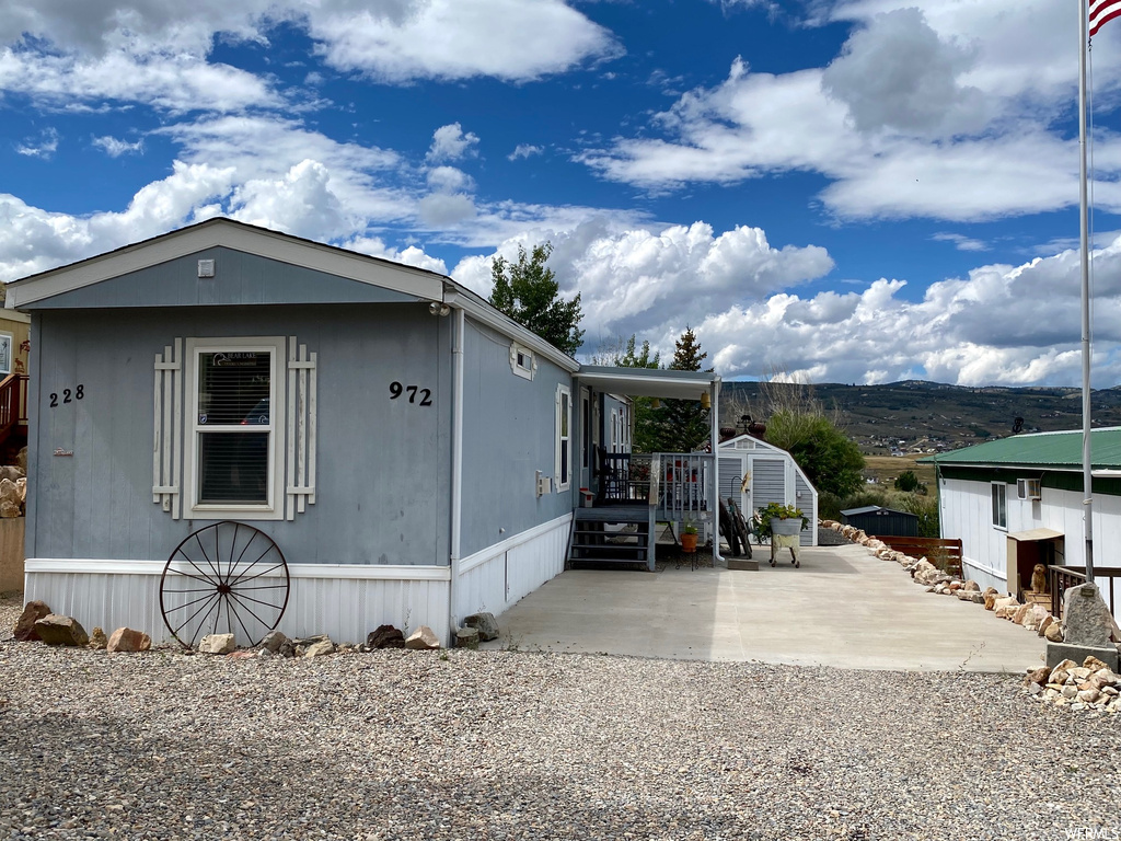 Manufactured / mobile home with a patio area, an outdoor structure, and a mountain view