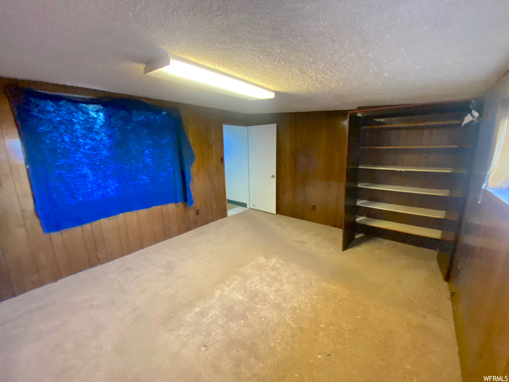 Basement with a textured ceiling and wooden walls