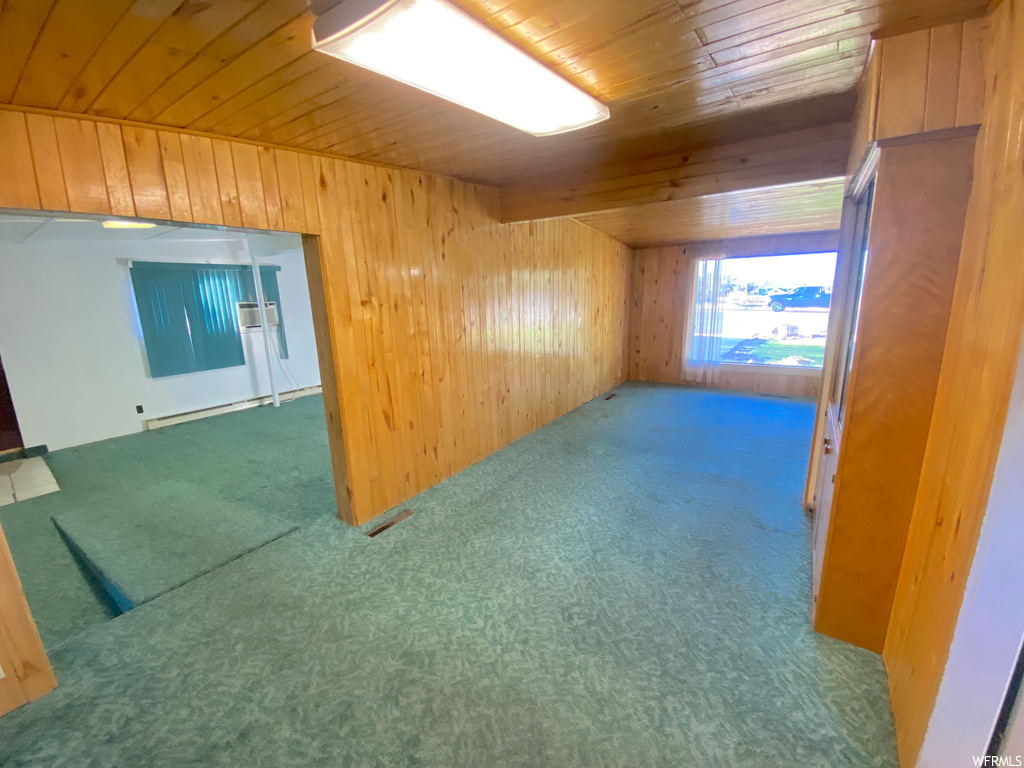 Interior space with wooden walls, light carpet, and wood ceiling