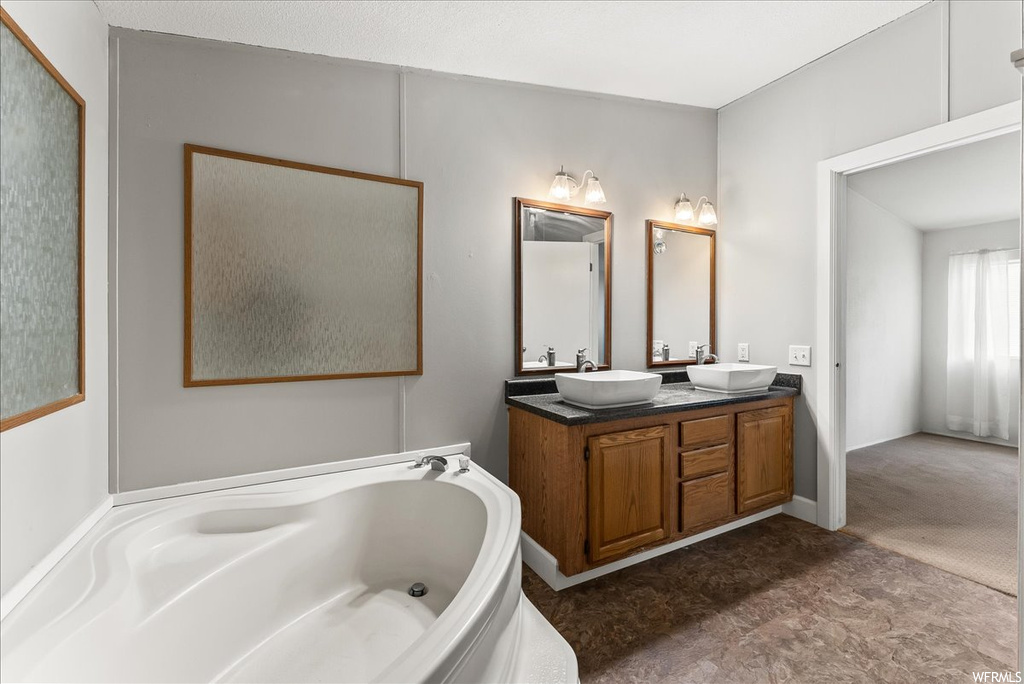 Bathroom featuring tile floors, mirror, double sink vanity, and a bath