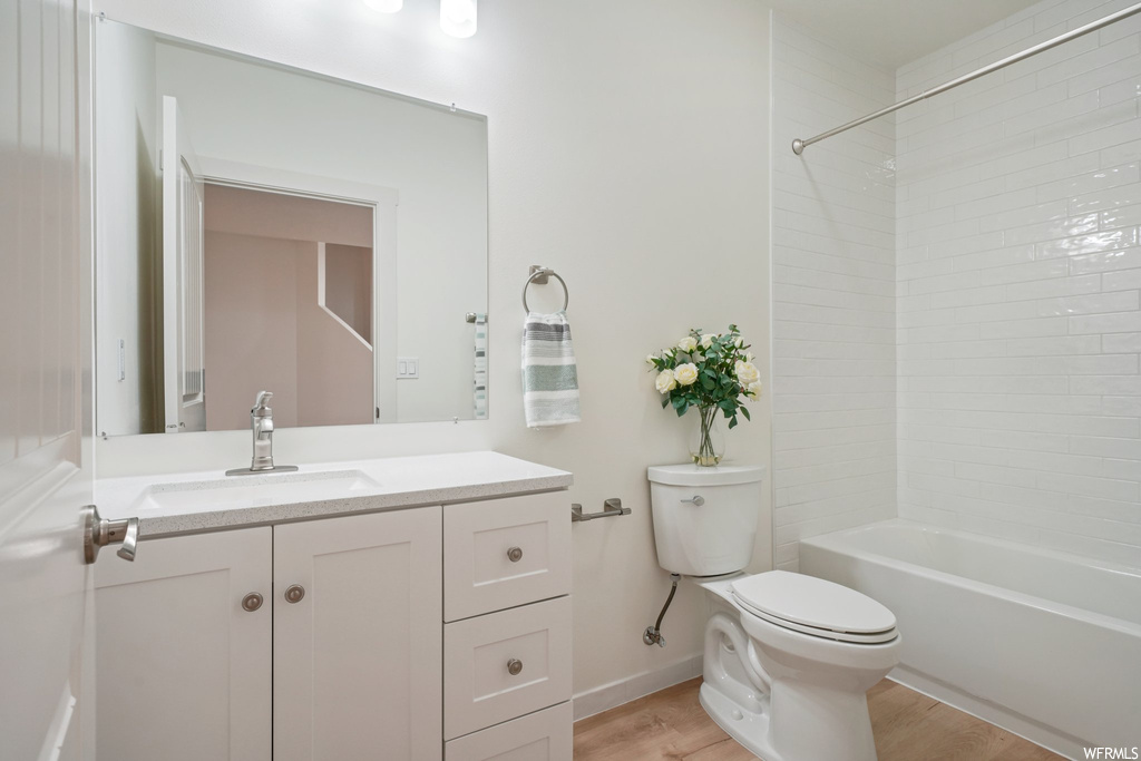 Full bathroom featuring tiled shower / bath combo, mirror, light hardwood floors, and large vanity
