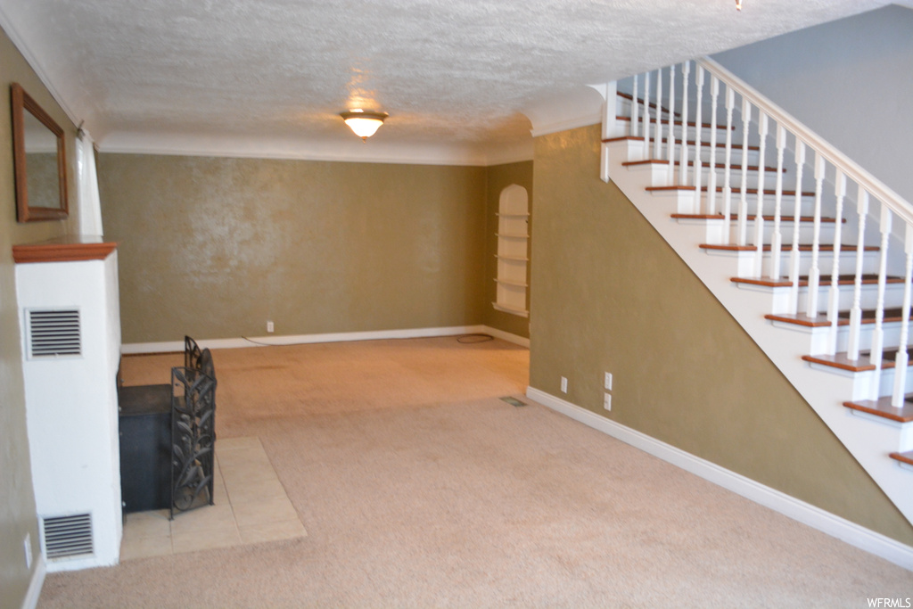 Unfurnished living room with light colored carpet and a textured ceiling