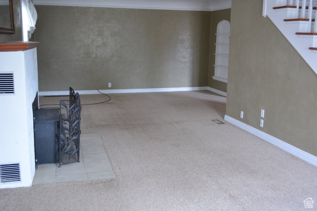 Unfurnished living room with crown molding and light colored carpet