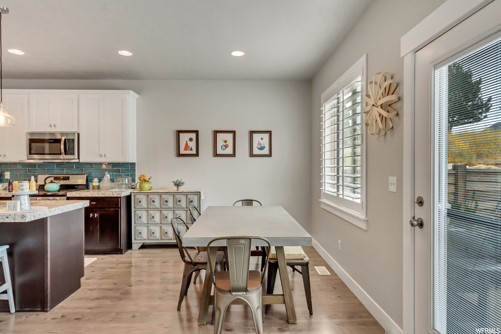 Kitchen with backsplash, range, white cabinets, light countertops, and light hardwood floors