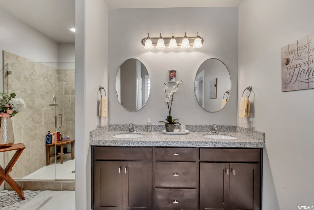 Bathroom with double vanity, mirror, and a shower with door
