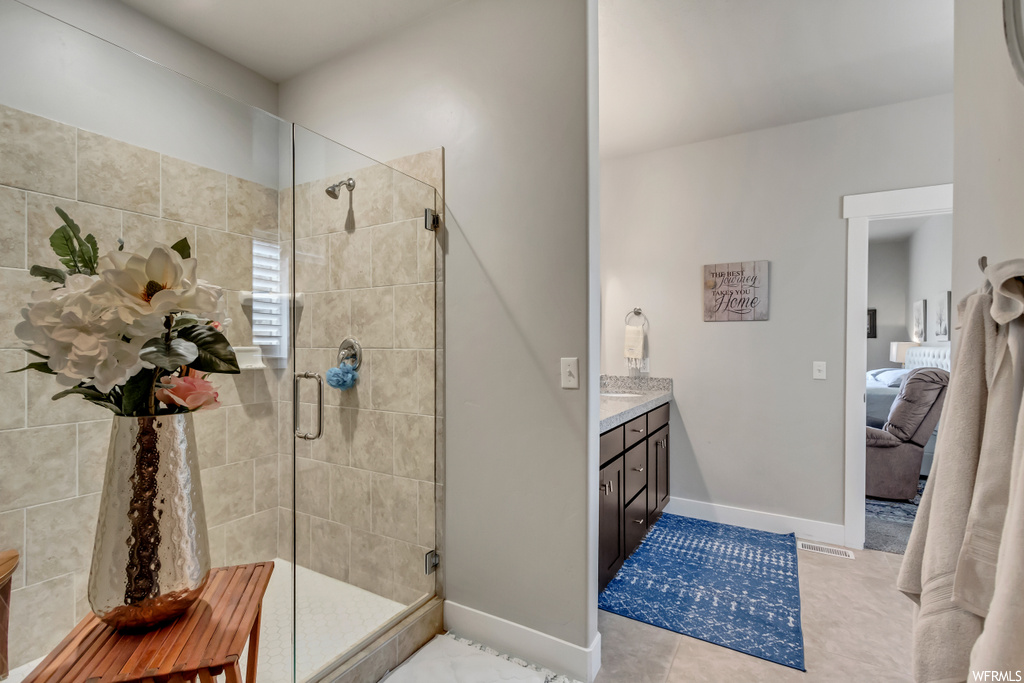 Bathroom with vanity, a shower with shower door, mirror, and light tile flooring